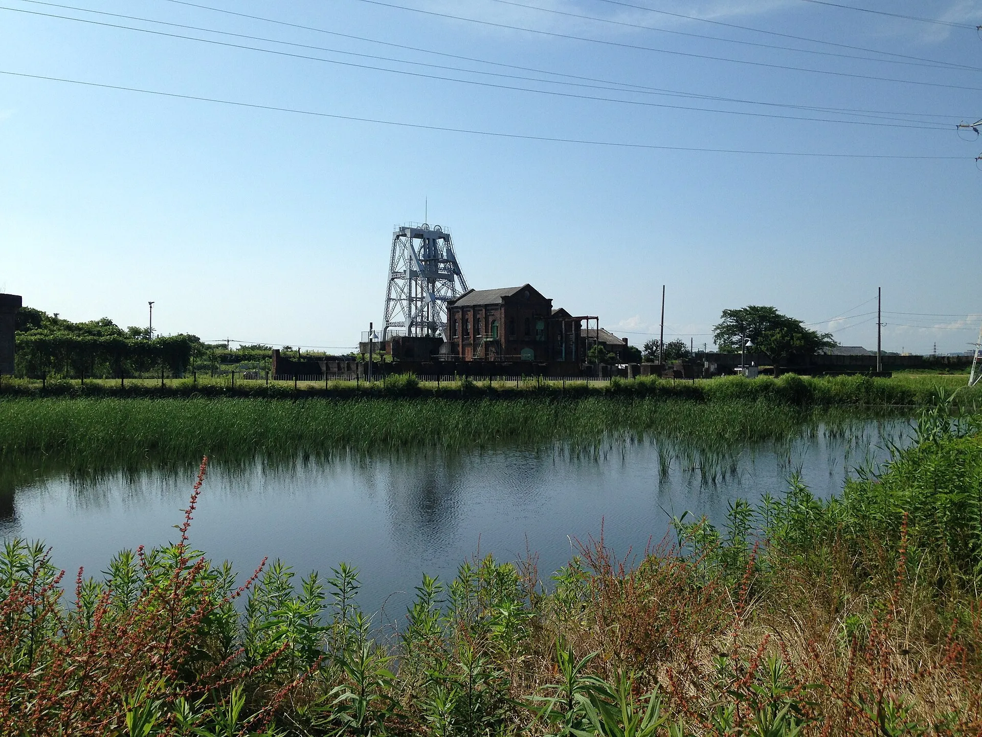 沈殿池の向こうに見える万田坑の立坑櫓と煉瓦の建物